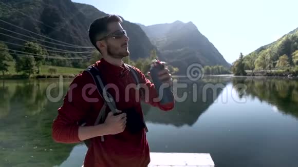 徒步旅行者带着背包喝水站在湖边视频的预览图