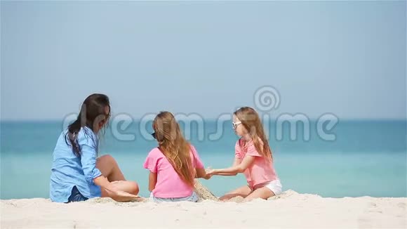 妈妈和小女儿在热带海滩上做沙堡视频的预览图