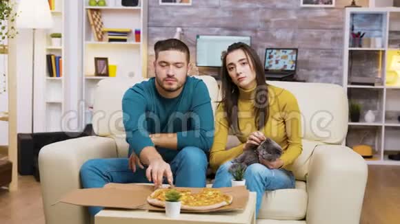 漂亮的年轻女人和男朋友坐在沙发上视频的预览图