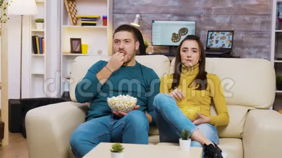 年轻夫妇在沙发上放松看电视视频的预览图