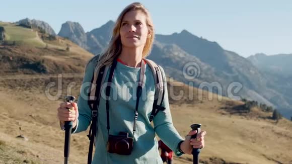 年轻漂亮的女旅行者带着背包在山上行走时向旁边看视频的预览图