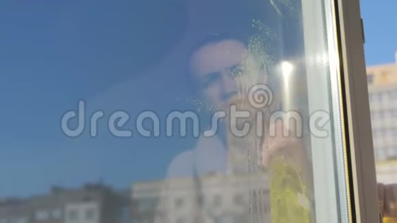 一个女人在肮脏的表面喷洒洗涤剂用抹布擦拭窗户从而清洗她的窗户视频的预览图