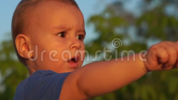 一个留着白发的2岁男孩看着骑自行车的人用手指指着他视频的预览图