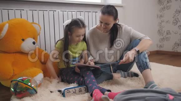 母女俩在房间里毛茸茸的地毯上读着一本儿童书视频的预览图