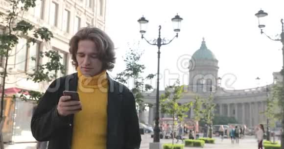 帅哥在等人他穿着黄色的毛衣和黑色的雨衣波什亚科努申纳亚街视频的预览图