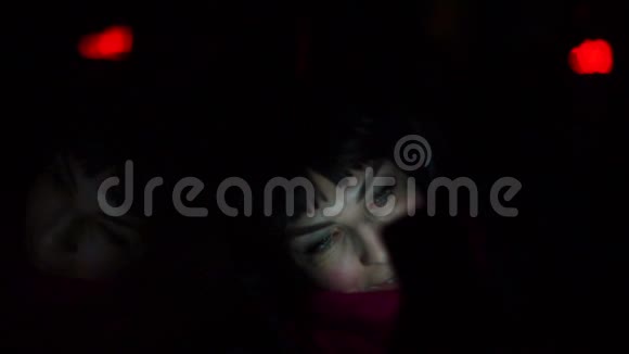 一个开朗的女孩在夜间公共汽车上看智能手机的屏幕视频的预览图