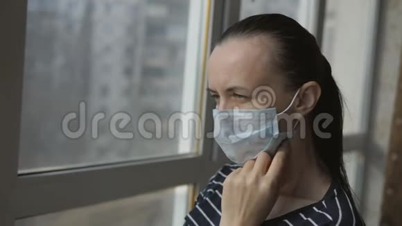窗户附近一个戴防护医疗面罩的女孩视频的预览图