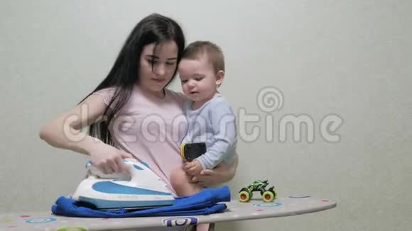 母亲挽着婴儿用另一只手臂熨烫视频的预览图