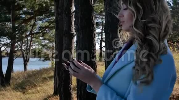 一位美丽的年轻女子在森林中投掷圆锥形针叶树视频的预览图