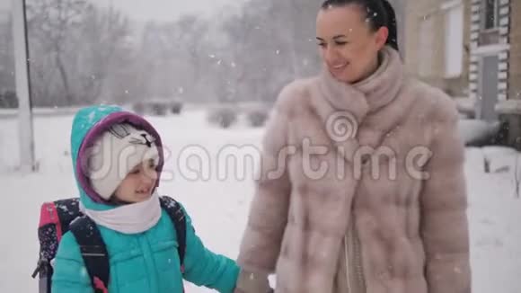 母亲和女儿在雪地里牵着手从学校回家视频的预览图