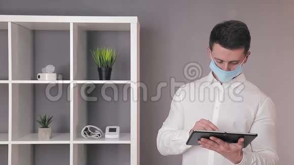 戴防护口罩的医生在他办公室的平板电脑里工作视频的预览图