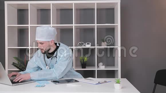 在电脑办公室工作的医生一位穿着医用服装的医生正在电脑上打字视频的预览图