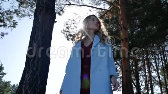 在晴朗的天气里秋天的森林里美丽的金发女郎披着外衣视频的预览图