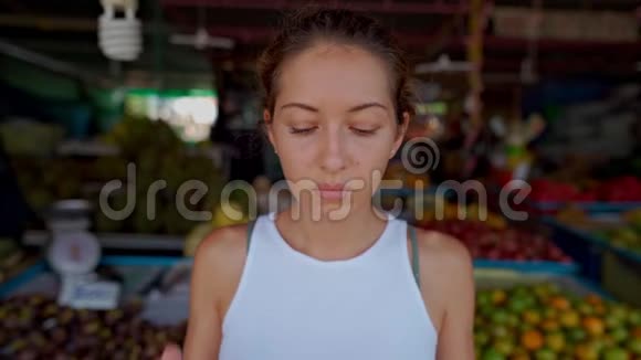 一个年轻的女人戴着防护面具站在市场上看着摄像机视频的预览图