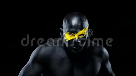 有女性双手的男人健美运动员有黄色的面部艺术和黑色的身体油漆彩色肖像视频的预览图