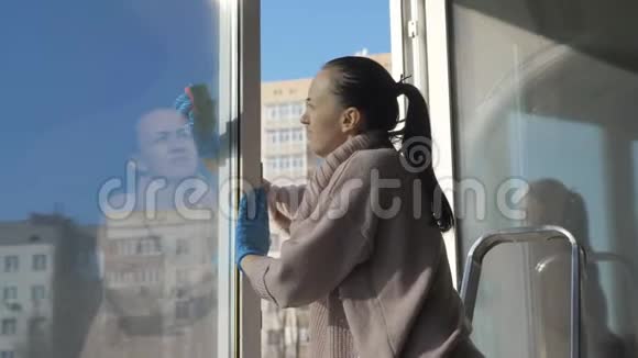 站在梯子上的女人在公寓里洗脏窗户视频的预览图