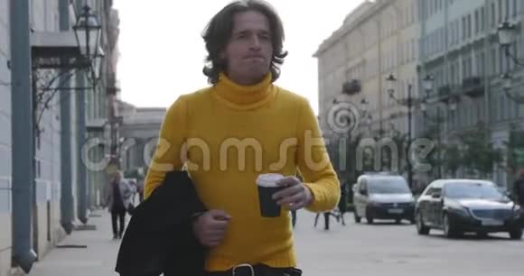 帅哥在等人喝咖啡他穿着黄色毛衣和黑色雨衣博尔沙亚视频的预览图
