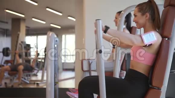 年轻女子在健身房的机器上锻炼胸部视频的预览图