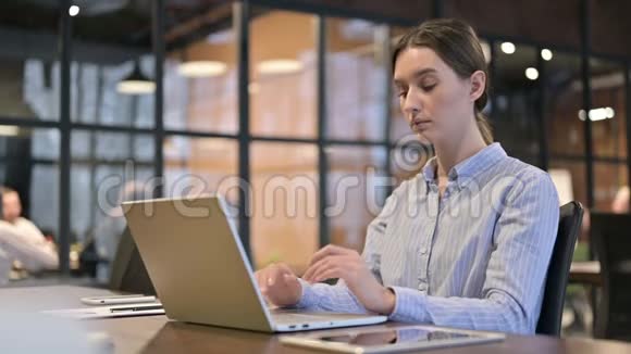 有头痛的女人在笔记本电脑上工作视频的预览图