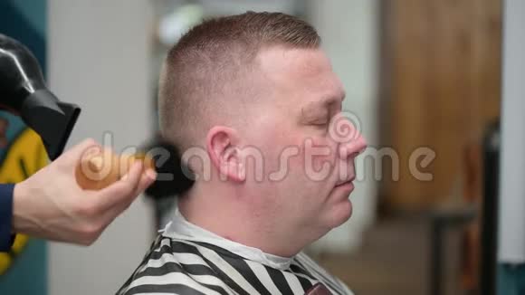 男人理发店理发主人的特写使用吹风机和刷子来完成发型视频的预览图