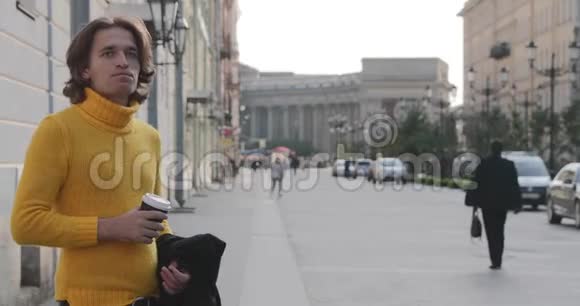 帅哥在等人喝咖啡他穿着黄色毛衣和黑色雨衣博尔沙亚视频的预览图