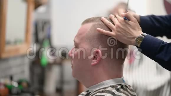 男人理发店理发大师用剪刀剪一个金发男人的特写镜头视频的预览图