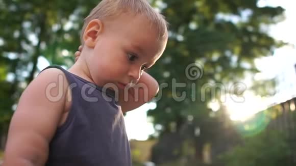 两岁的白发男孩站在操场上挠头视频的预览图