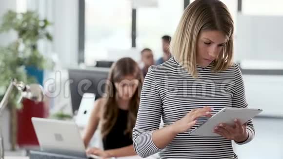 在现代创业办公室两位与数字平板电脑合作的商业年轻女性视频的预览图