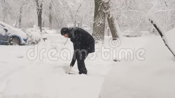 一个拿着铲子的人在后院下雪视频的预览图