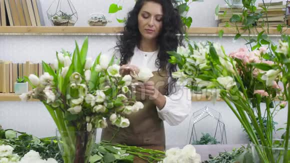 年轻迷人的女花店商人在他的花店里做一束花出售人民视频的预览图