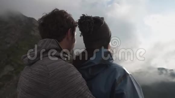 一对年轻幸福的夫妇拥抱着站在山崖上向前看视频的预览图