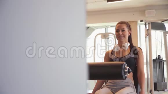 年轻女子在健身房锻炼腿部伸展和腿部卷曲机视频的预览图