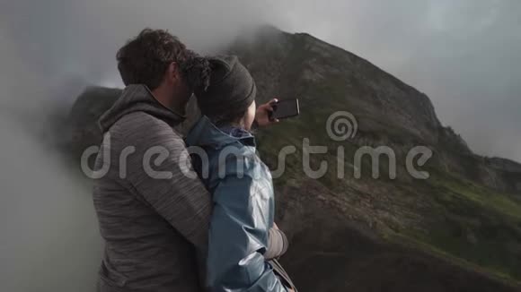 一对年轻夫妇在悬崖上拥抱拥抱拍了一张自拍照片视频的预览图