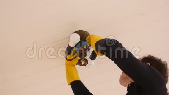 戴乳胶手套的电工擦拭天花板上的灰尘清洁和洗涤灯视频的预览图