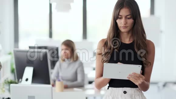 微笑的年轻女商人与数码平板电脑和看相机在现代创业办公室视频的预览图