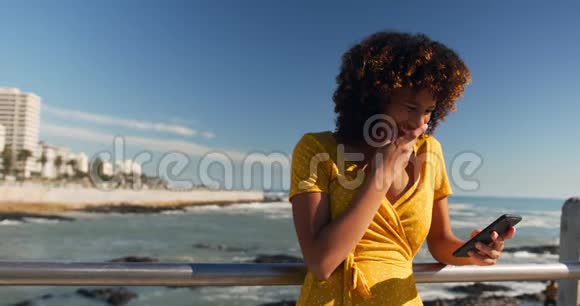 女人微笑着在海滩上用电话视频的预览图