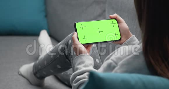 带空白绿色屏幕的女孩手持手机的背面视图视频的预览图