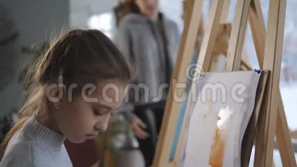 坐在画架前的小女孩画着丙烯酸颜料视频的预览图