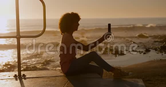 日落时分在沙滩上自拍的女人视频的预览图