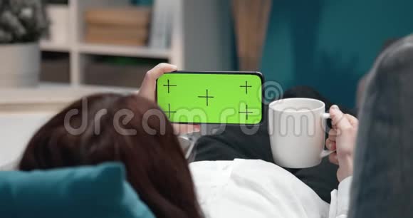 女孩躺在沙发上用智能手机的后视图视频的预览图