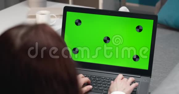 从后面的女孩使用带有色度键屏幕的笔记本电脑查看视频的预览图