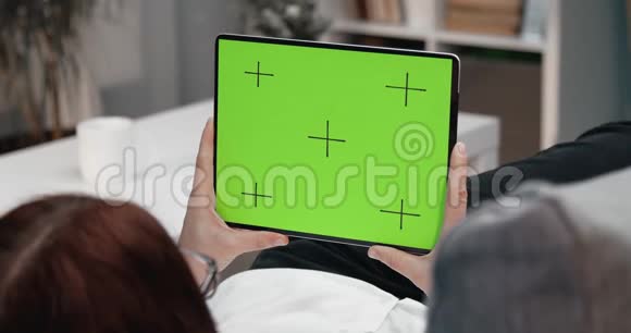 年轻女子拿着平板电脑看着绿色的屏幕视频的预览图