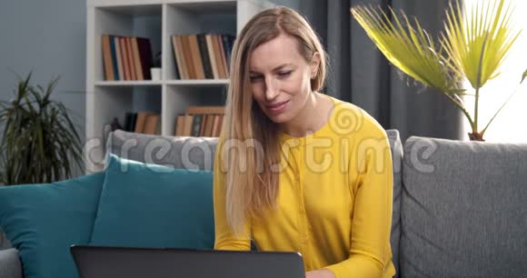 坐在沙发上工作的快乐女人视频的预览图