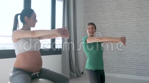 美丽的孕妇和她的理疗师做普拉提运动准备分娩视频的预览图