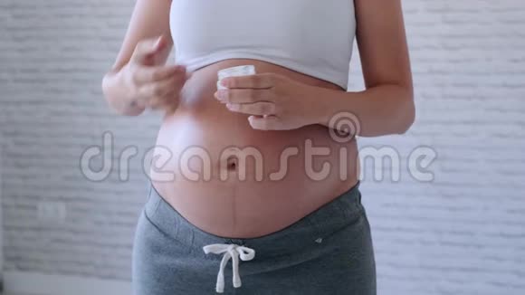 孕妇在怀孕的腹部涂上护肤霜以防止拉伸痕迹视频的预览图