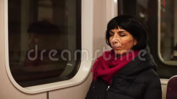 坐地铁火车的一个困倦的女人到达车站视频的预览图