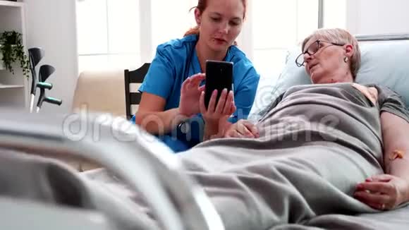 女护士帮助老妇人使用智能手机视频的预览图