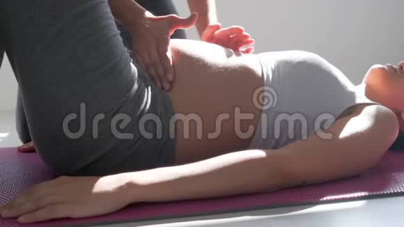 物理治疗师帮助美丽的孕妇做普拉提运动准备分娩视频的预览图