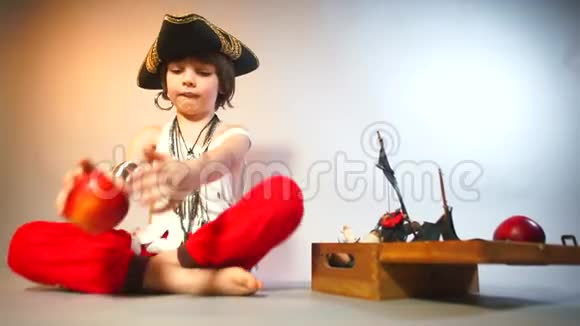 一个穿着海盗服装的男孩在浅色背景上玩苹果视频的预览图