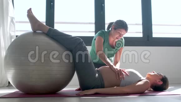 物理治疗师帮助美丽的孕妇做普拉提运动与球准备分娩视频的预览图